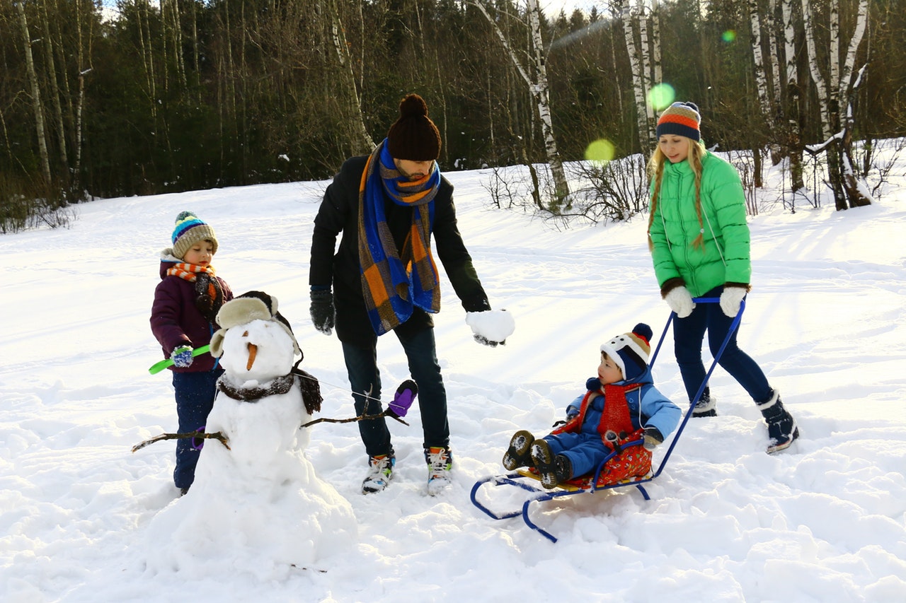 Familie leger i sne med vintertøj